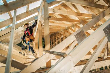 Arbeider klatrer i rammeverk på hus